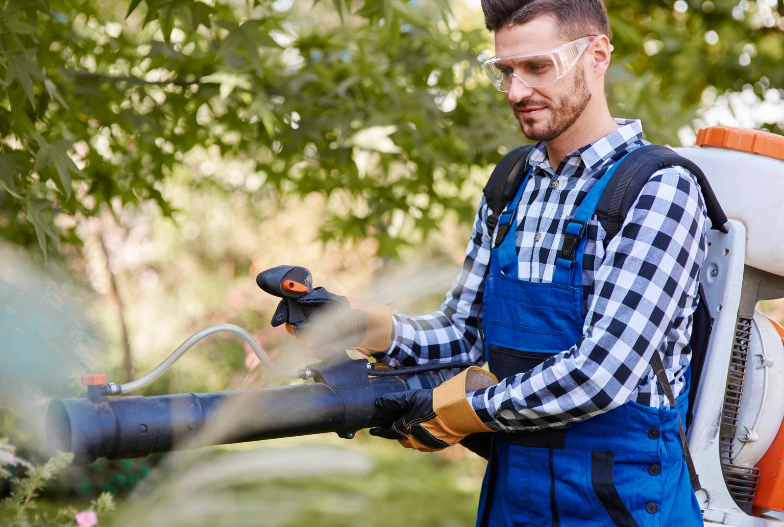 Gardener using leaf blower at garden