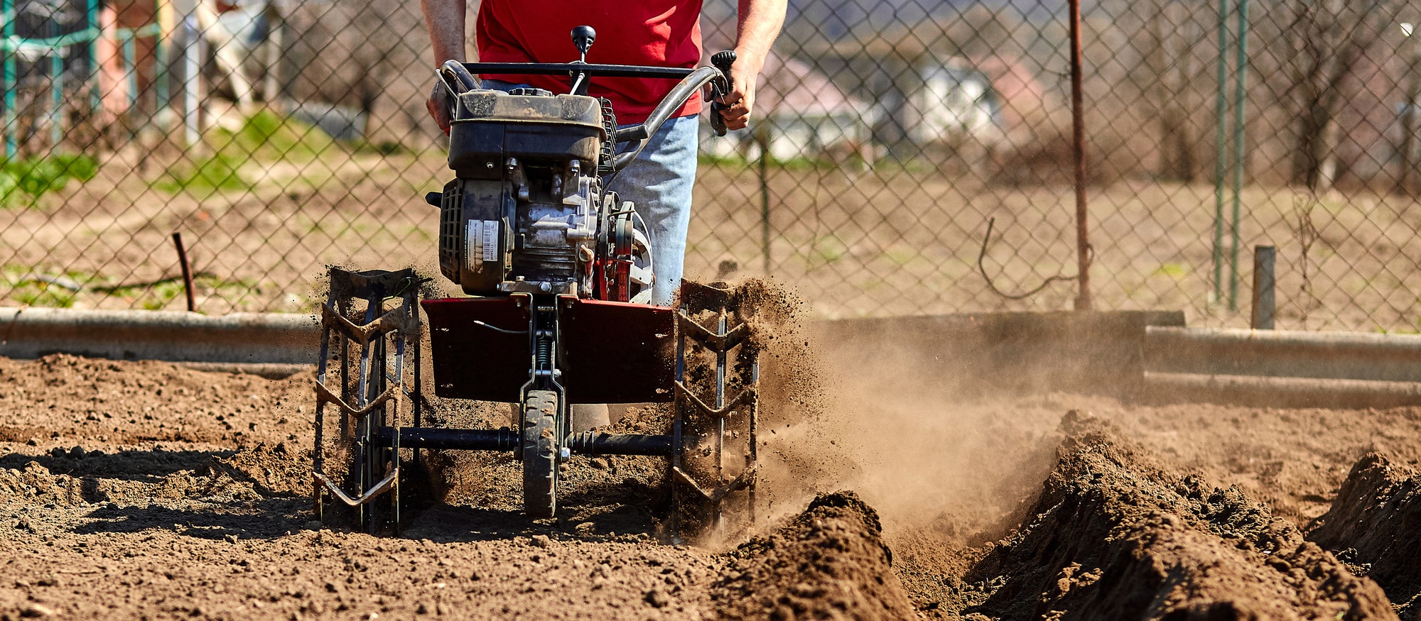 Gardener cultivate ground soil with tiller tractor or rototiller, cutivator